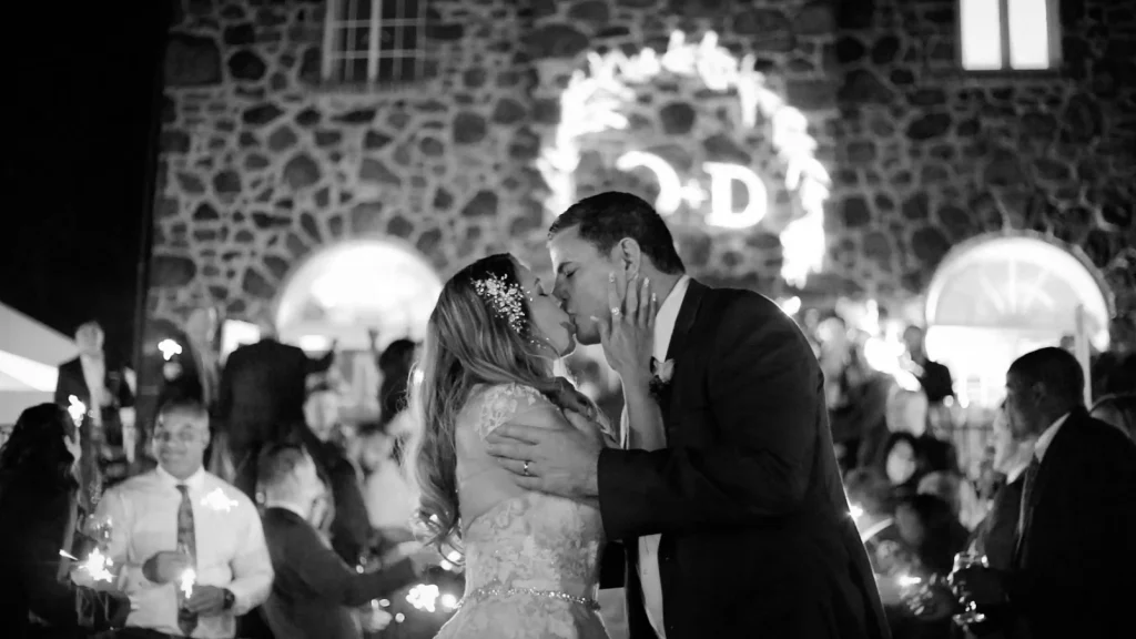 a couple, at poplar springs manor, kissing in front of a sparkler exit and custom gobo light with initials "O + D"