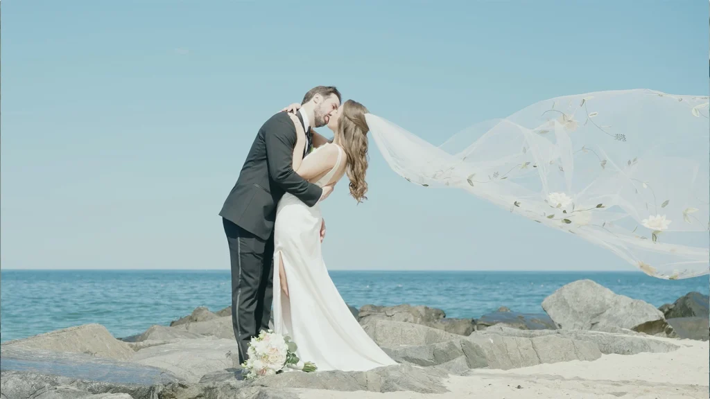 Bride & groom kissing with veil flowing in wind at, Virginia Beach